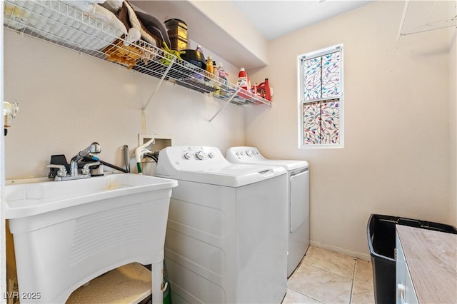 laundry area with a sink, separate washer and dryer, light tile patterned floors, baseboards, and laundry area