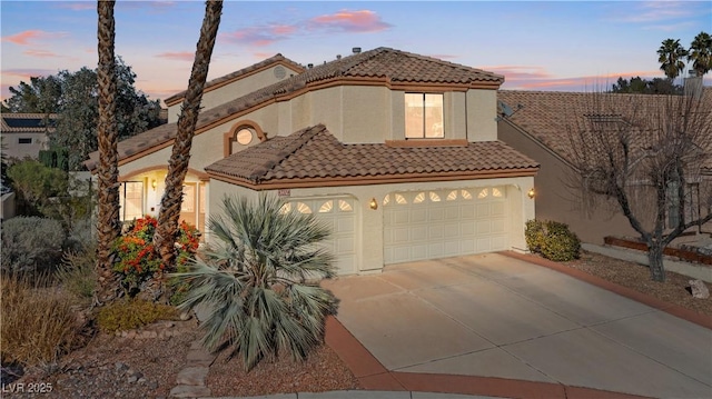 mediterranean / spanish-style home with driveway, stucco siding, and a tiled roof