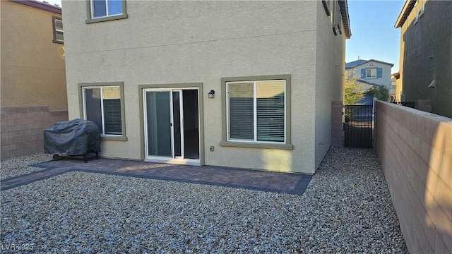 back of house featuring a gate, fence, a patio, and stucco siding