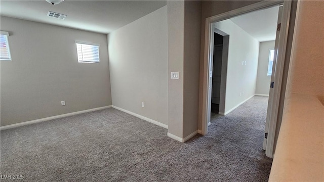 carpeted spare room featuring visible vents and baseboards