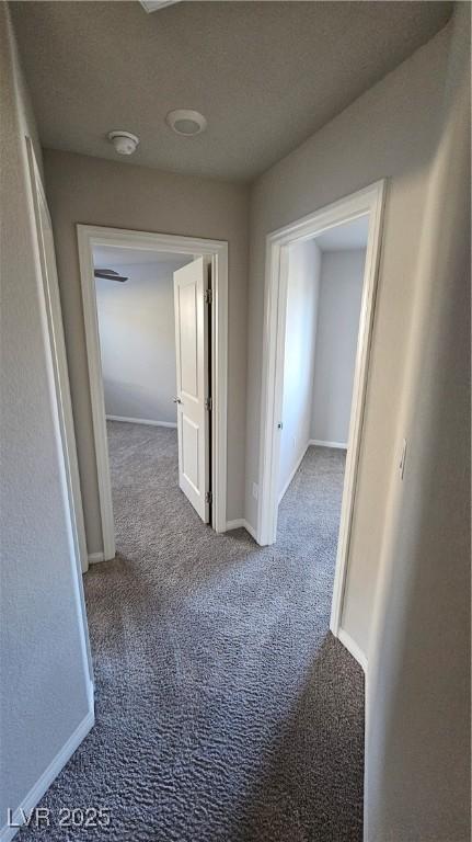 hall with a textured ceiling, carpet flooring, and baseboards