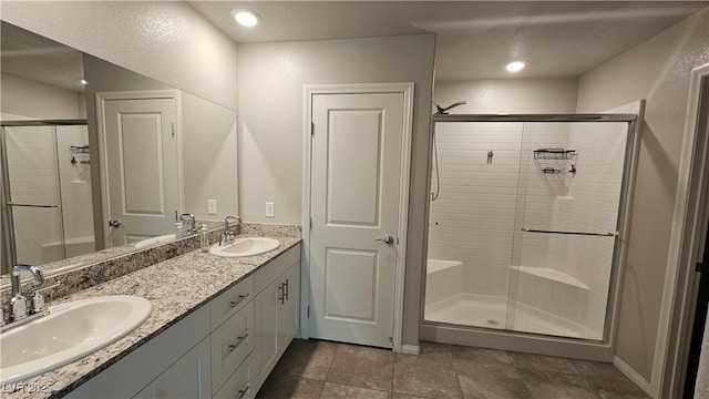 bathroom with double vanity, a stall shower, and a sink