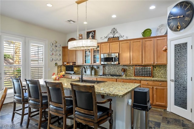 kitchen with brown cabinetry, visible vents, stainless steel appliances, and a sink