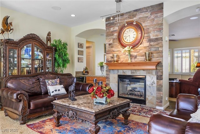 living area with arched walkways, a fireplace, and recessed lighting