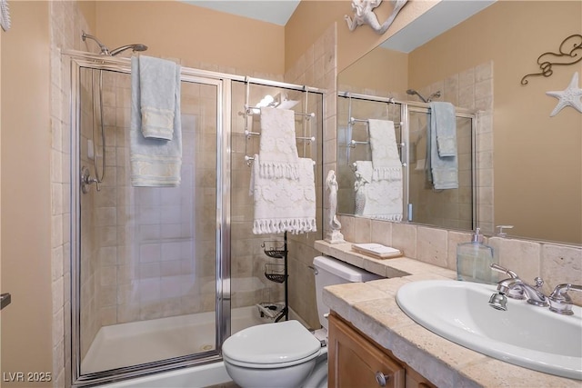 full bathroom featuring a stall shower, vanity, and toilet