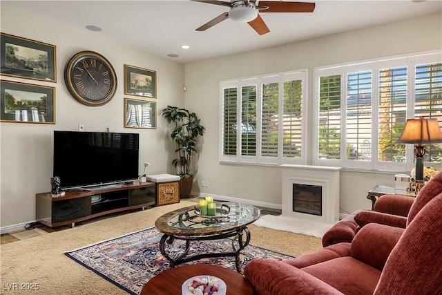 living area with recessed lighting, baseboards, a ceiling fan, and a glass covered fireplace