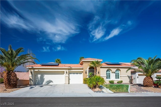 mediterranean / spanish home featuring driveway, a tiled roof, an attached garage, and stucco siding