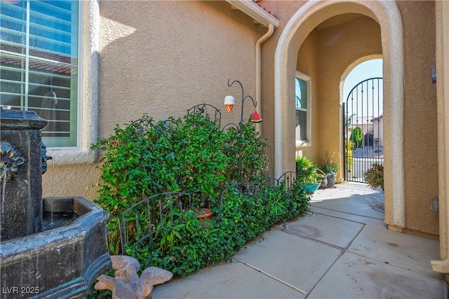 view of exterior entry featuring a gate and stucco siding