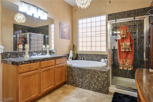 bathroom with a stall shower, a notable chandelier, a bath, and vanity