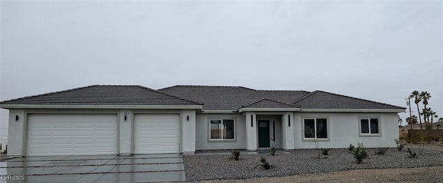 view of front of house featuring driveway, a tiled roof, an attached garage, and stucco siding