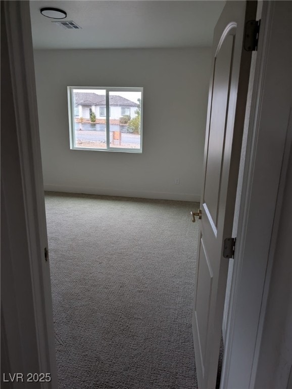 carpeted empty room featuring baseboards and visible vents