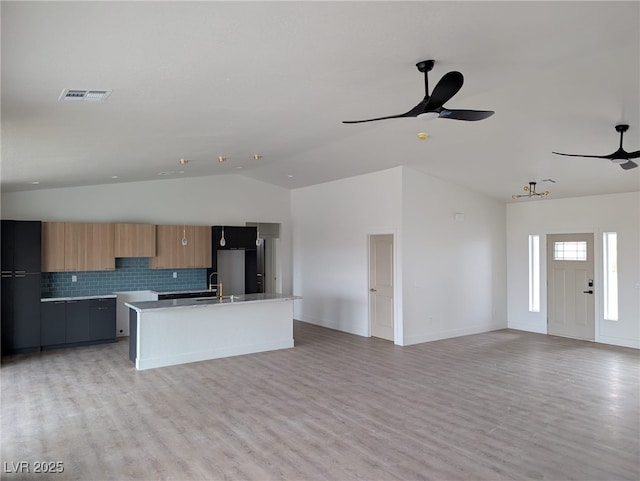 kitchen featuring light wood finished floors, a center island with sink, a ceiling fan, modern cabinets, and a sink