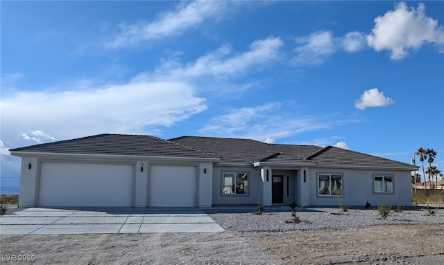 single story home with a garage, concrete driveway, a tile roof, and stucco siding