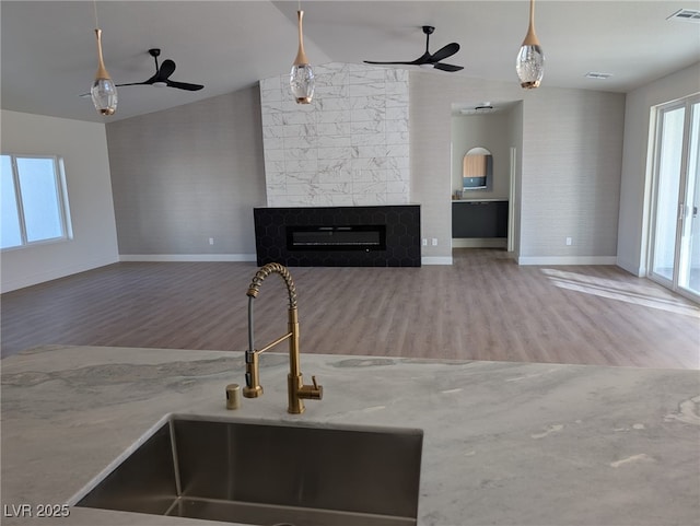 unfurnished living room featuring a tile fireplace, vaulted ceiling, visible vents, and a sink