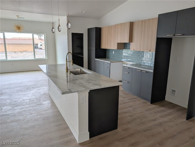 kitchen with tasteful backsplash, a sink, light wood finished floors, and modern cabinets