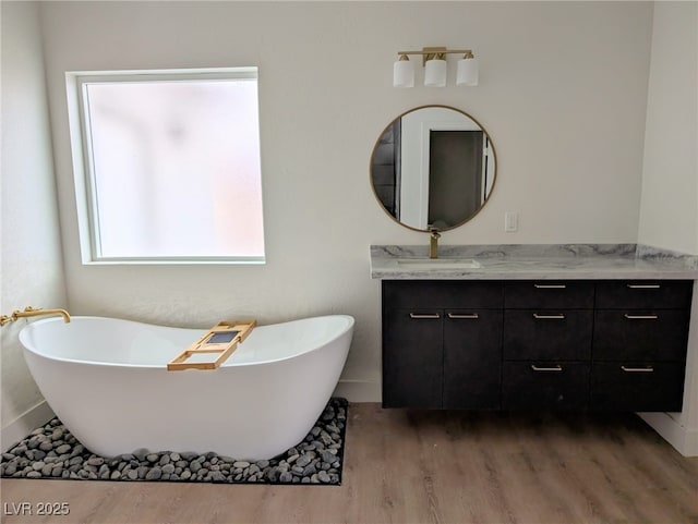 full bath with a freestanding tub, wood finished floors, and vanity