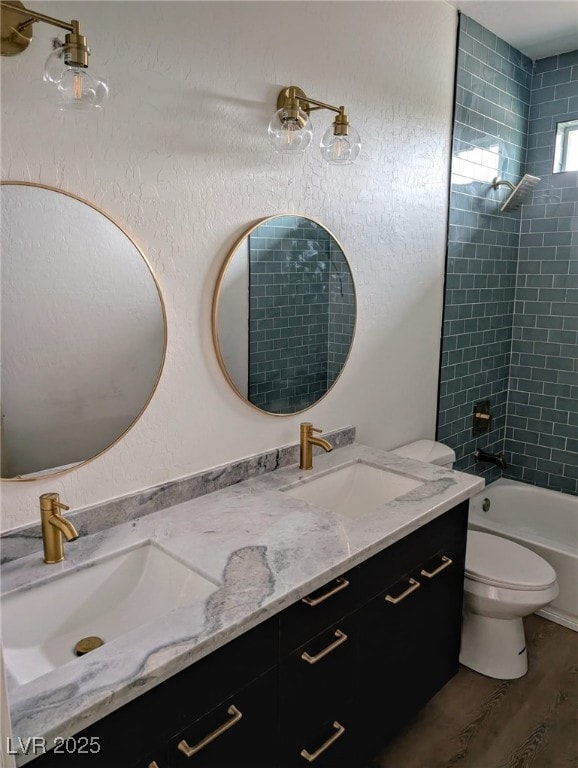 bathroom with double vanity, wood finished floors, a sink, and toilet