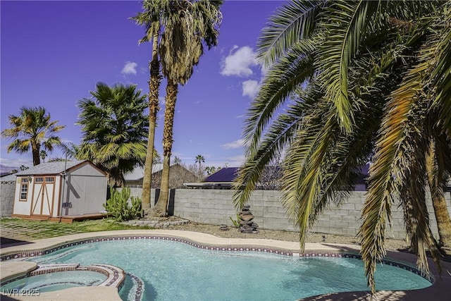 view of pool with a storage unit, an outdoor structure, a fenced backyard, and a pool with connected hot tub