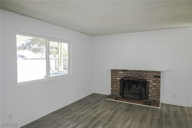 unfurnished living room featuring a fireplace, a textured ceiling, baseboards, and wood finished floors