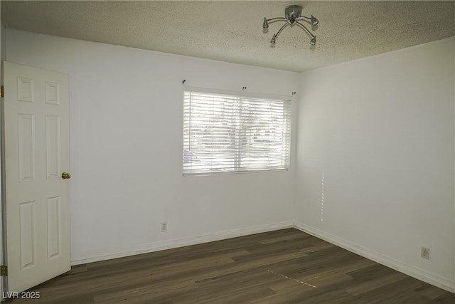 spare room with a textured ceiling, baseboards, and dark wood-style flooring