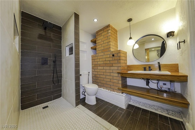 full bathroom with toilet, a textured ceiling, wood finish floors, a walk in shower, and a sink