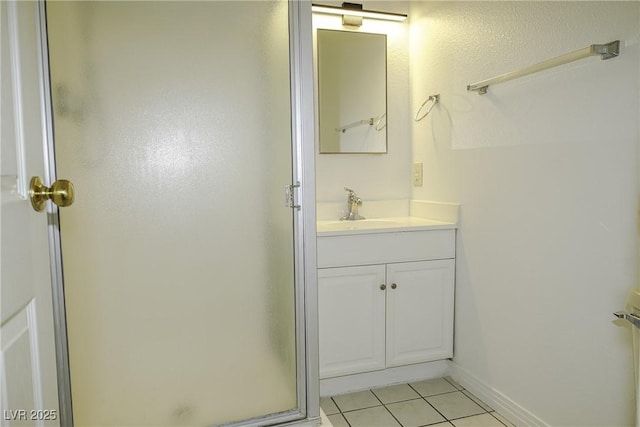 bathroom with a stall shower, tile patterned floors, baseboards, and vanity