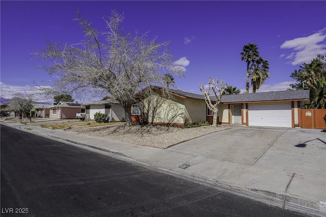 view of front of home with concrete driveway, an attached garage, and stucco siding