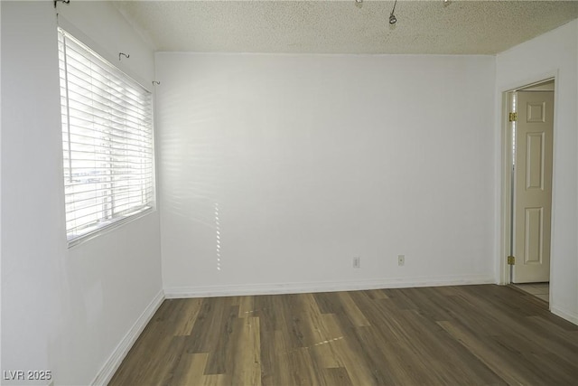 spare room with a textured ceiling, baseboards, and wood finished floors