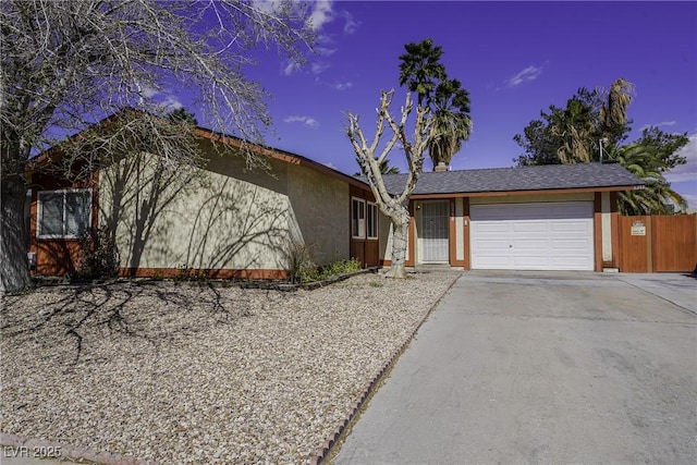 ranch-style home with a garage, fence, driveway, and stucco siding