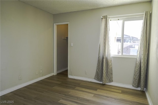 spare room featuring a textured ceiling, baseboards, and wood finished floors