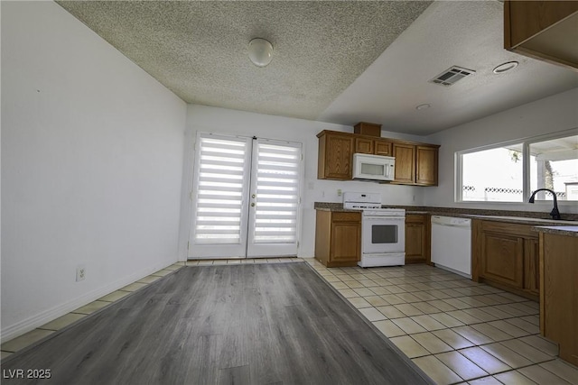 kitchen featuring plenty of natural light, white appliances, visible vents, and a sink