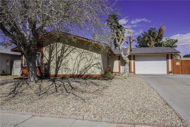 ranch-style home with a garage, fence, concrete driveway, and stucco siding