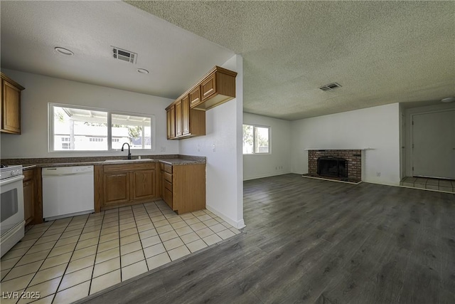 kitchen with white appliances, a fireplace, visible vents, and a sink