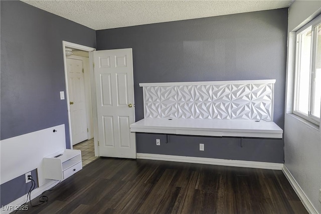 interior space featuring a textured ceiling, wood finished floors, and baseboards