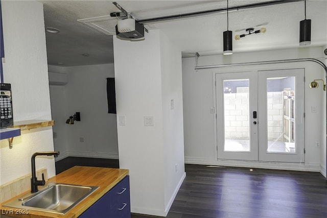 kitchen with dark wood-style floors, french doors, blue cabinetry, wooden counters, and a sink