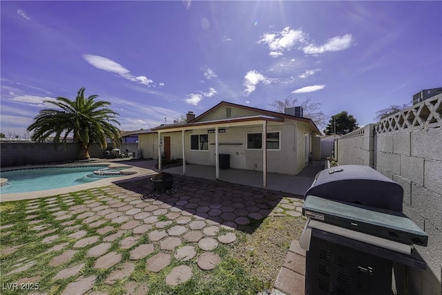 back of property with a patio, a fenced backyard, central air condition unit, a pool with connected hot tub, and stucco siding