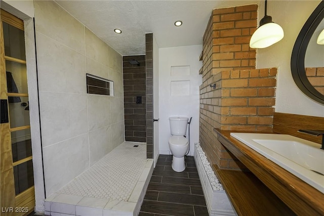 bathroom featuring a walk in shower, a textured ceiling, toilet, recessed lighting, and vanity