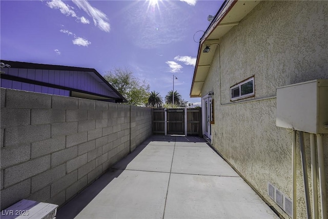 view of property exterior with fence, a patio, and stucco siding