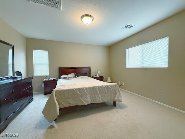 bedroom with multiple windows, visible vents, and light colored carpet