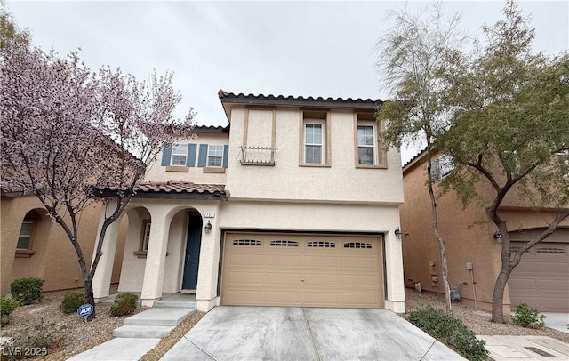 mediterranean / spanish home featuring a garage, concrete driveway, a tile roof, and stucco siding