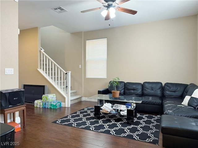 living area with stairway, a ceiling fan, visible vents, and wood finished floors