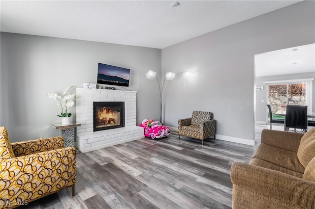 living room with vaulted ceiling, a fireplace, wood finished floors, and baseboards