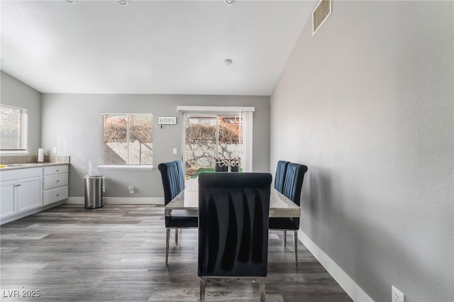 dining room with lofted ceiling, wood finished floors, visible vents, and baseboards