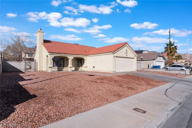 mediterranean / spanish house with driveway, a tiled roof, an attached garage, fence, and stucco siding