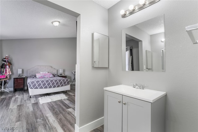 bathroom featuring connected bathroom, vanity, a textured ceiling, wood finished floors, and baseboards