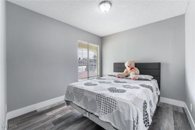 bedroom with a textured ceiling, baseboards, and wood finished floors