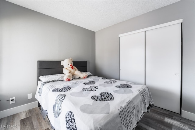 bedroom with a textured ceiling, a closet, wood finished floors, and baseboards