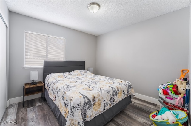 bedroom featuring a closet, a textured ceiling, baseboards, and wood finished floors