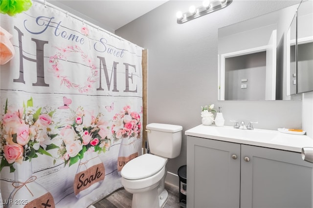 bathroom with toilet, a shower with shower curtain, and vanity