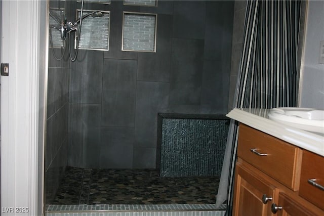 full bathroom with a tile shower and vanity